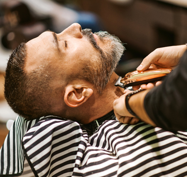 Barber trims the beard of the customer