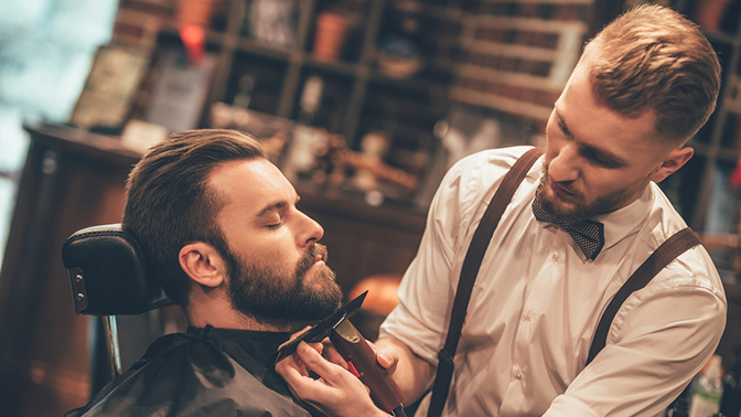 Grooming of real man. Side view of young bearded man getting bea